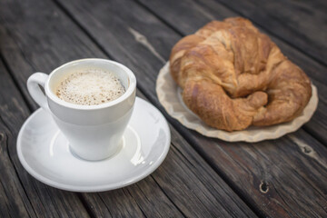 Fresh bakery. Cozy background for a coffee shop. Black coffee and croissant. French breakfast. Wooden table. Aromatic drink. Restaurant theme. Morning meal. Office food.