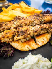 Grilled souvlaki, French fries with tzatziki and fresh vegetables