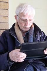 Senior male is glued on his ipad. Older generation like him now embracing new technology because of self isolation.