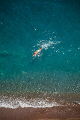 Obraz premium A man is swimming in the clear water of the Costiera Amalfitana
