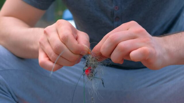 Man untangles a fishing line and hooks preparing to fishing, hands closeup. Fishing equipment and tools for catching fish.