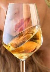 white wine glass in the foreground close-up. woman lips with red lipstick blurred in background
