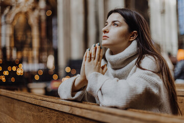 religion, faith, harmony and people concept: a woman praying on her knees in an ancient Catholic...