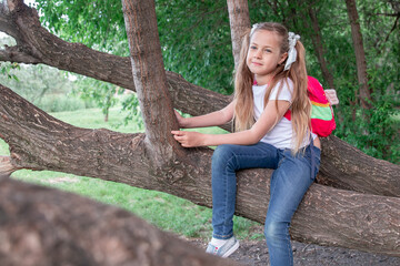 a little girl sits on a tree in the woods, in the park. child and tree