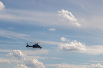 Helicopter flies through cloudy sky.