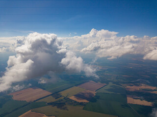 High flight in the clouds over agricultural fields in summer.