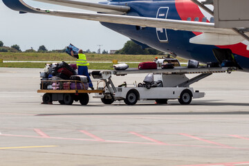 Airport staff unload luggage from a plane.