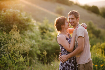 Happy young woman and man in romantic relationship hugging and kissing at sunset.