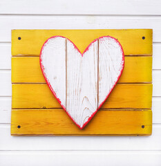 Wooden heart on a yellow and white background from boards