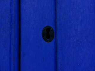 Black keyhole on bright blue wooden panelled door with copyspace