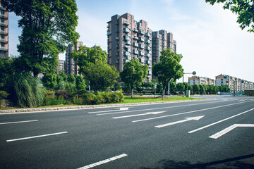 Clear sky, asphalt road with traffic guide lines beside high-rise buildings in the city