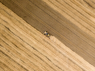 Obraz premium Aerial drone view. The harvester harvests wheat in the Ukrainian field.