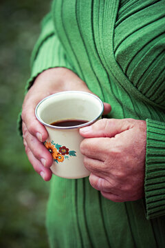 Close up of senior female hands, holding a warm cup of coffee.