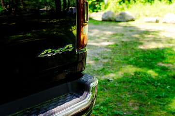 Chrome 4x4 logo on black background. Black truck with a 4x4 logo in the forest in nature with a blurred background.