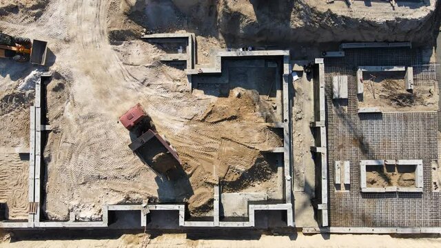 Large construction of a residential complex. The truck pours sand. The foundation is laid. Top to bottom view. Aerial view over the crane.