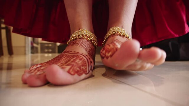 Close up of cute indian woman foots with traditional mehendi painted and gold jewelry. Girl funny stomping her feet