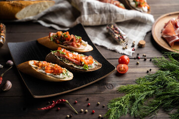 From above plate with palatable bruschettas placed on lumber table near napkin and various cooking ingredients