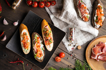 Top view of delicious sandwiches placed on square plate near cloth napkin and fresh ingredients on wooden table