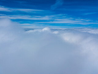 Naklejka na ściany i meble High flight in white curly clouds.
