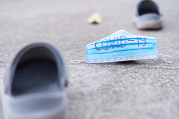 The medical masks used for the protection against coronavirus left on the road. The concept of stepping through COVID-19. 