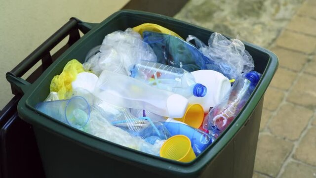 Waste bin full of plastic waste such as plastic bottles, cups, plastic bags and other plastic packaging ready for recycling