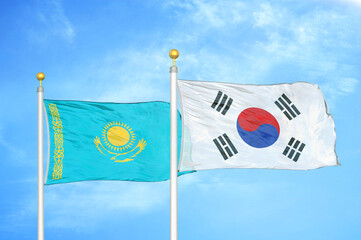 Kazakhstan and South Korea two flags on flagpoles and blue sky