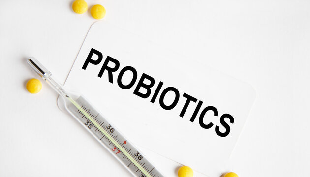 On the table are pills, a thermometer, leaves and a notebook with the inscription -PROBIOTICS. The concept of medicine.