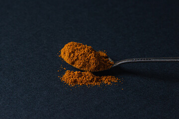 Red ground pepper on a black background. A spoonful of red ground pepper. Spicy seasoning