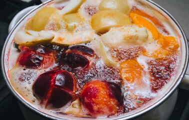 Fruit compote: apricots, plums, apples, cherries are cooked in a metal pan in boiled water with bubbles. Making juice on the stove.