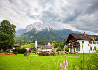 Mountain panorama in front of cloud sky scene. Grainau, bavarian alps village against cloudy Sky. domed church with Mountains (Waxenstein and Zugspitze peaks). Wetterstein range Bavaria Bayern Germany