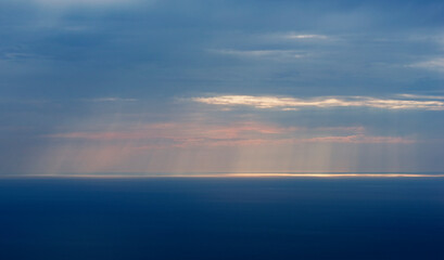 Sun rays shining through clouds at sea