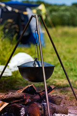 Camping bowler hat hangs over the fire on a tripod