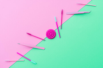 Flat lay style beauty business background.  Complementary colour palette of pink and teal green showing eyelash extension or lash artist tools and treatment products