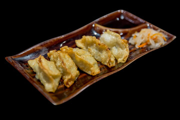 Gyoza stuffed with soy sauce - Japanese cuisine on black isolated.