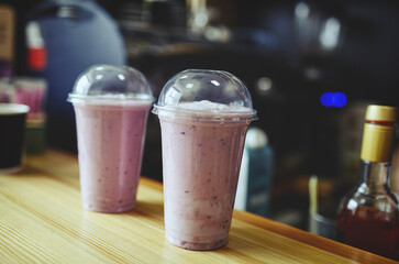Strawberry milkshake covered in plastic glass on table in cafe.Blurred image,selective focus