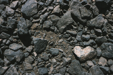 Heart shaped white stone among dark volcanic rocks background with copy space. Seen in Lanzarote, Canary Islands, Spain. 