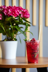Mojito cocktail or soda drink with lime,raspberry and mint on table in bar.Blurred image,selective focus