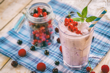 non-alcoholic milkshake smoothie with fresh currant, raspberry and mint leaves on a wooden background