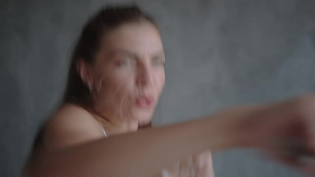 A woman boxing with and jumping on a home trampoline.
