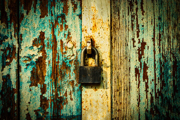 Lock on weathered planks of gates painted in blue