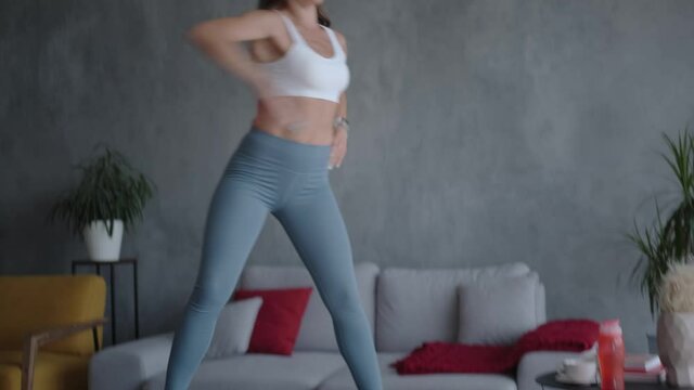 Young athletic woman exercising at home alone using a trampoline