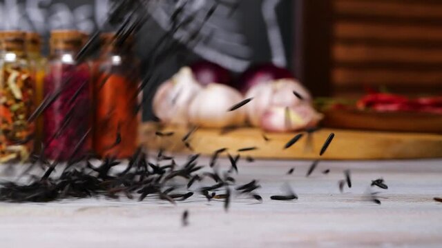 Bunch of seeds of black cumin falling and spreading on table in kitchen