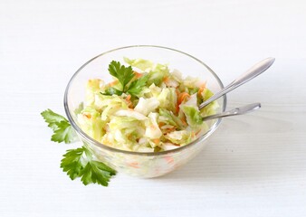 Fresh cabbage and carrot salad with parsley in a bowl on a white background