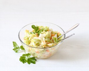 Fresh cabbage and carrot salad with parsley in a bowl on a white background