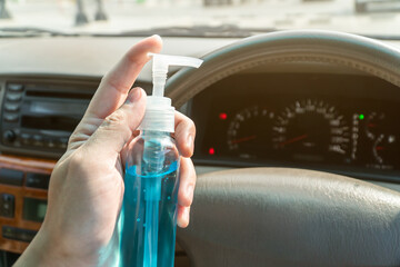 Close up hand holding alcohol spray in car. Hand sanitizer spray for clean car steering wheel and against the corona virus, covid-19, bacteria. Hand cleanser.