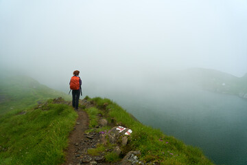 Obraz premium Woman hiking by a lake in the mountains