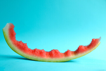 Fresh sliced watermelon isolated on blue background. Eaten watermelon. Peel. Minimal creative concept. Place for text. Bright healthy summer food.