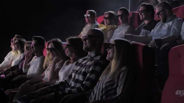 Close-up of excited cinema-goers in 3d glasses enjoying visit to 4dx cinema hall of movie theater. Enthusiastic audience watching movie with special effects while chairs shaking and water spraying