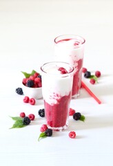 Milk berry refreshing drink, cocktail with ice cream, fresh raspberries and blackberries in a glass on a white background