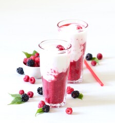 Milk berry refreshing drink, cocktail with ice cream, fresh raspberries and blackberries in a glass on a white background